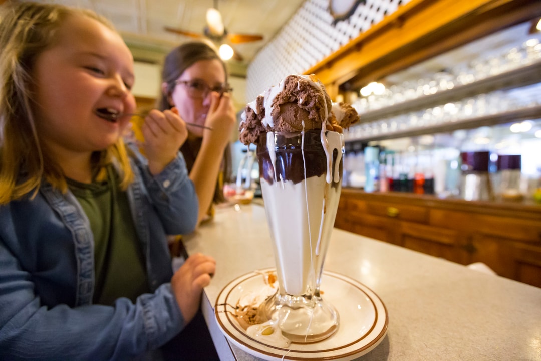 A mother and daughter share a sundae in a milkshake glass called a Tin Roof Sundae at Potter Sundry in Potter, Nebraska.