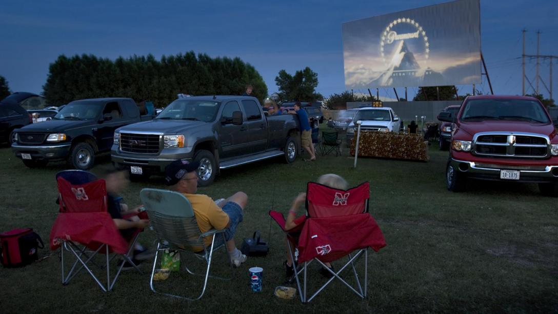 A family relaxes in lawn chairs as a movie flashes onto the giant screen at TK-Starlight Drive-In near Neligh, NE.