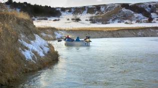 Group floating down the river in a stock tank surrounded by a snowy landscape.