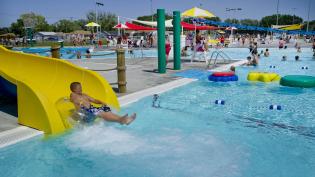 A child riding on an inner tube splashes into the pool at the end of a slide at a water park in Nebraska.