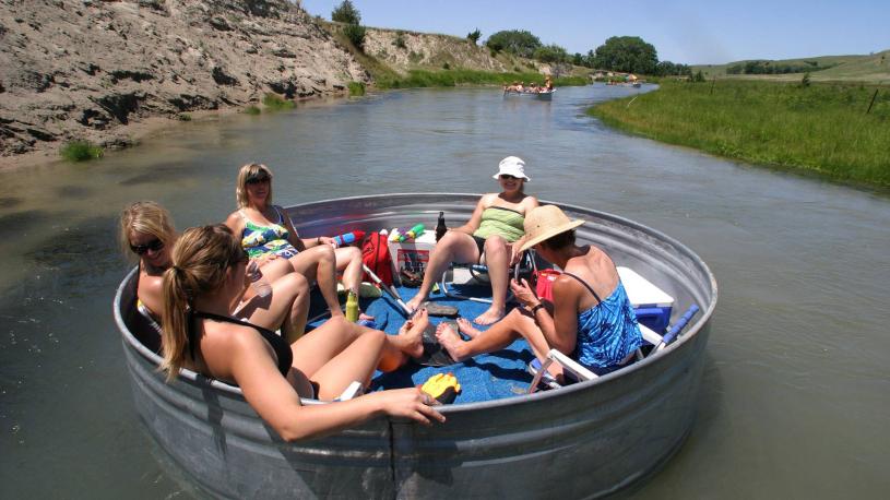 A group lounging in a livstock tank floating down a Nebraska river.