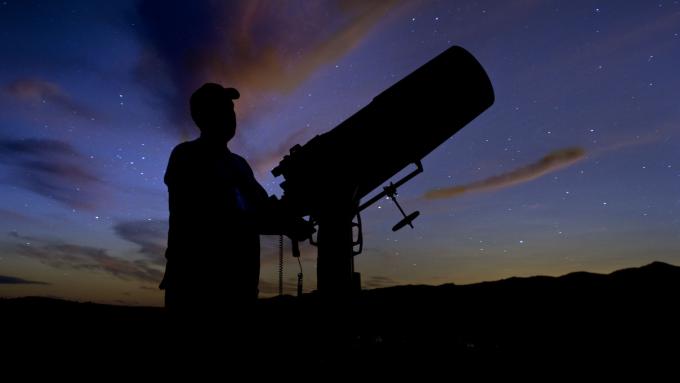 A person maneuvers a telescope to look at the darken sky at Merritt Reservoir State Recreation Area in Valentine, NE.